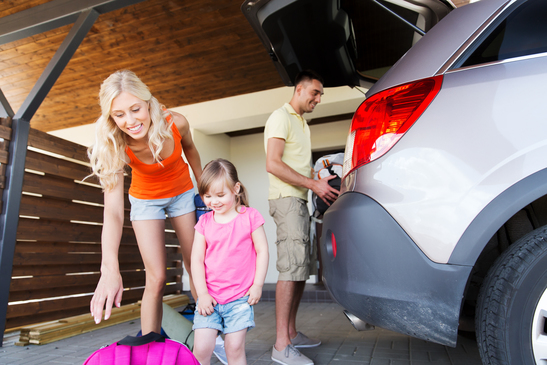 happy family packing things to car at home parking